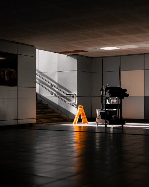 A close-up of a person wearing dark clothing and brown cleaning gloves, gently adjusting a lightbox sign that reads 'CLEANING HOME' on a wooden surface in a modern, minimalist living room with a sofa,